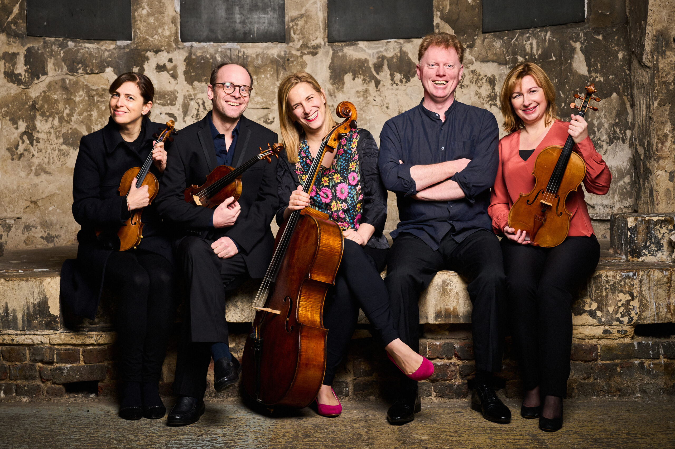 Five classical musicians from Ensemble 360 pose together, seated and smiling. They are our resident musicians in Sheffield and nationally.